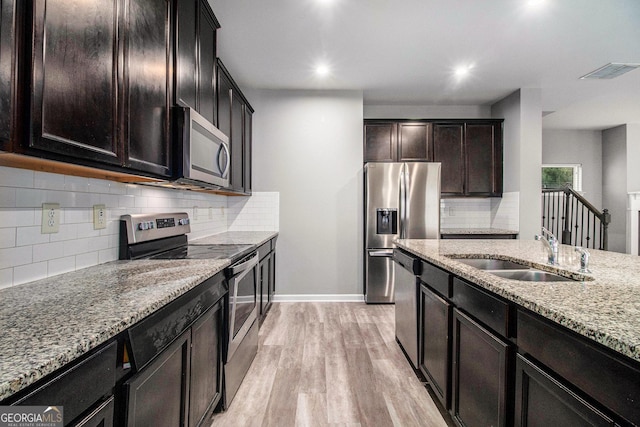 2769 Morgan Spring Trl, Buford, GA 30519 - kitchen featuring stainless steel appliances, a sink, light stone countertops, light wood-style flooring, and decorative backsplash