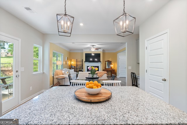 dining space with a chandelier, ceiling fan, a fireplace, baseboards, and crown molding