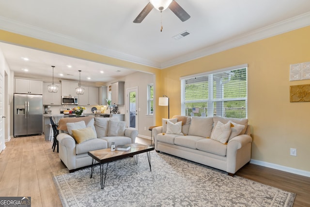 living room with light wood-style flooring, baseboards, a ceiling fan, recessed lighting, and crown molding
