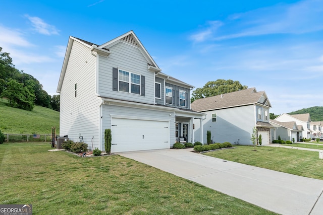 view of front of home with an attached garage, concrete driveway, a front yard, and central air condition unit