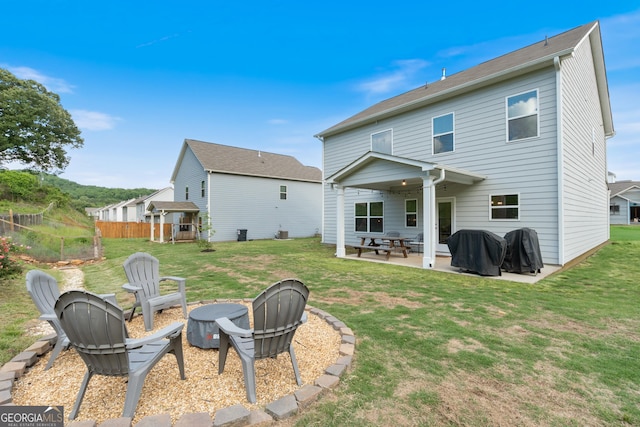 back of property with a patio, a fire pit, and a lawn