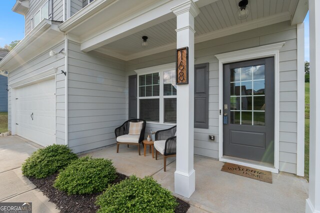 view of exterior entry with covered porch, a garage, and driveway