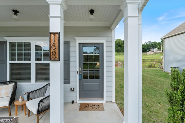 doorway to property with a porch and a yard