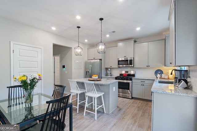 kitchen featuring appliances with stainless steel finishes, a center island, backsplash, a kitchen bar, and recessed lighting