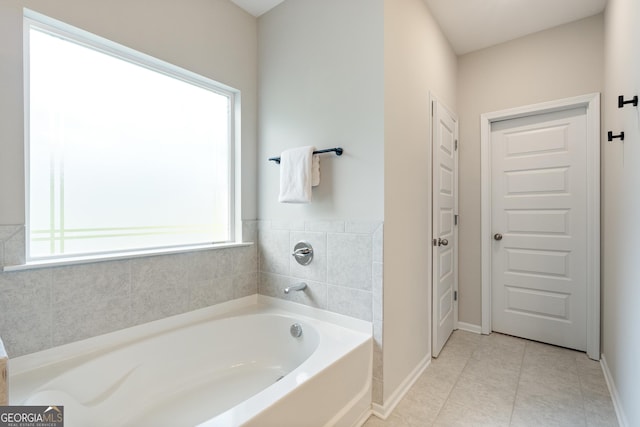 bathroom with a garden tub, baseboards, and tile patterned floors