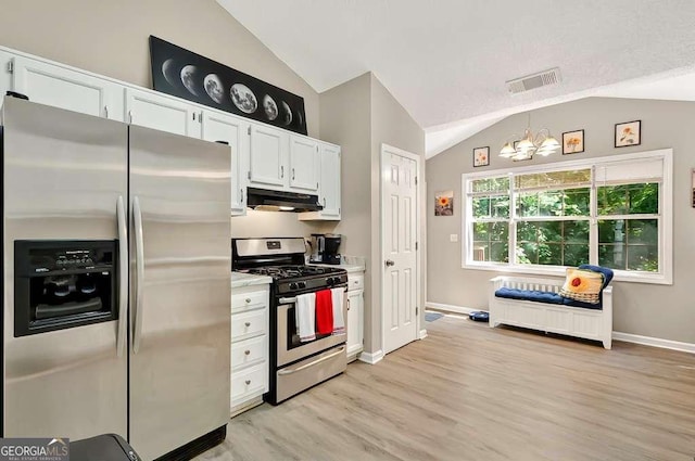 kitchen with stainless steel appliances, under cabinet range hood, vaulted ceiling, a chandelier, and white cabinets