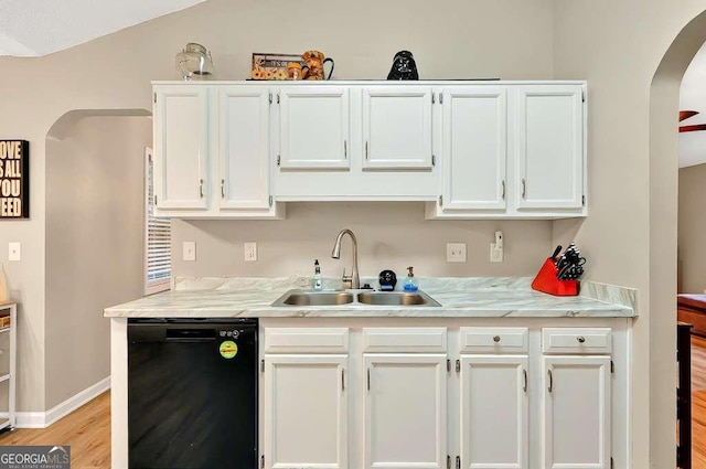 kitchen with dishwasher, a sink, arched walkways, white cabinetry, and light countertops