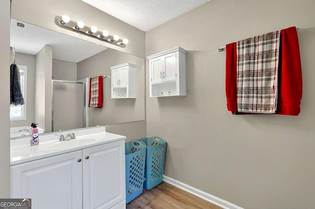 full bath with a shower stall, wood finished floors, vanity, and baseboards