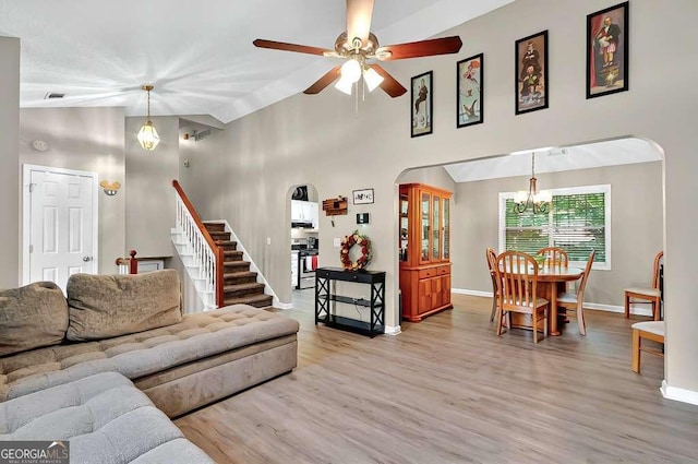 living area with arched walkways, a chandelier, baseboards, wood finished floors, and ceiling fan