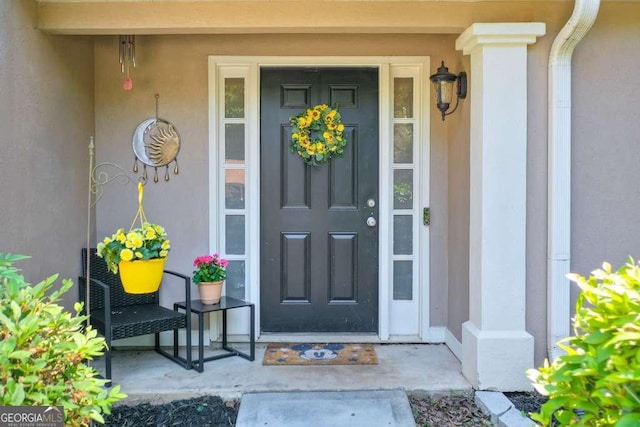 doorway to property with stucco siding and a porch