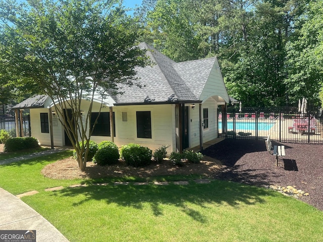 view of property exterior featuring roof with shingles and a community pool