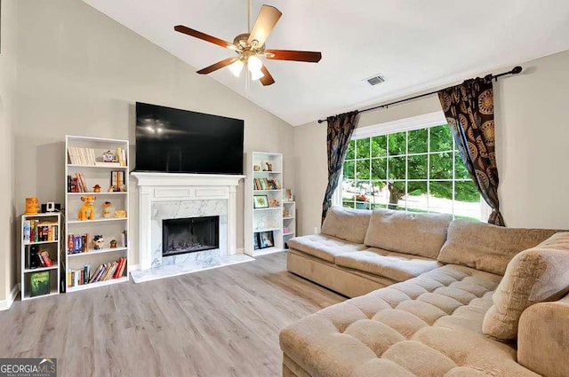 living area featuring ceiling fan, wood finished floors, a high end fireplace, and high vaulted ceiling