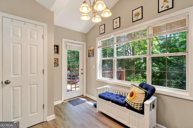 entryway with vaulted ceiling, baseboards, a chandelier, and wood finished floors
