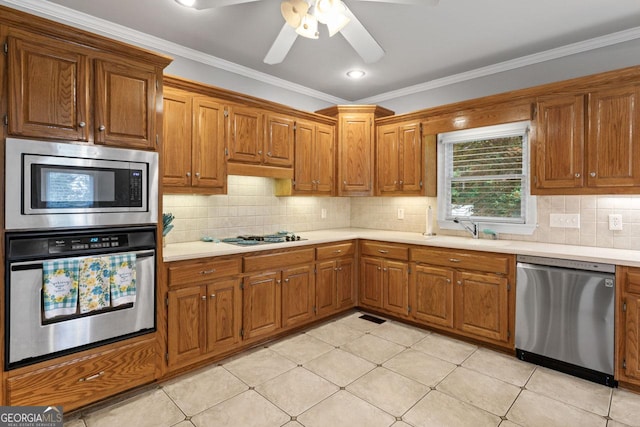 510 Jenna Trl, Mcdonough, GA 30252 - kitchen with appliances with stainless steel finishes, a sink, light countertops, brown cabinetry, and ornamental molding
