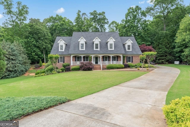 510 Jenna Trl, Mcdonough, GA 30252 - cape cod house featuring a porch, brick siding, a front lawn, concrete driveway, and view of wooded area