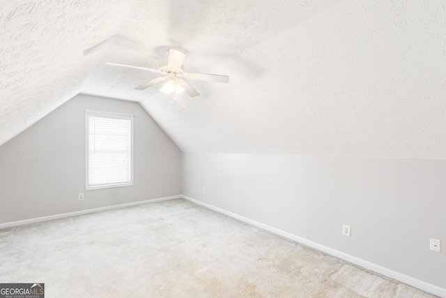 bonus room featuring a textured ceiling, baseboards, vaulted ceiling, carpet flooring, and ceiling fan