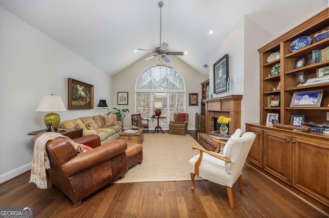 living room with a ceiling fan, a tiled fireplace, dark wood-type flooring, and high vaulted ceiling