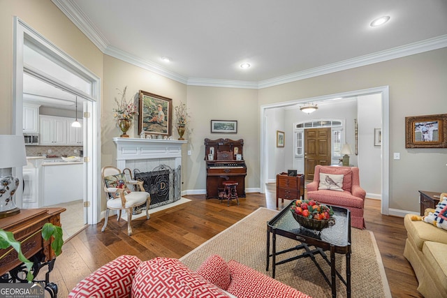 living room featuring crown molding, hardwood / wood-style flooring, a tiled fireplace, baseboards, and recessed lighting