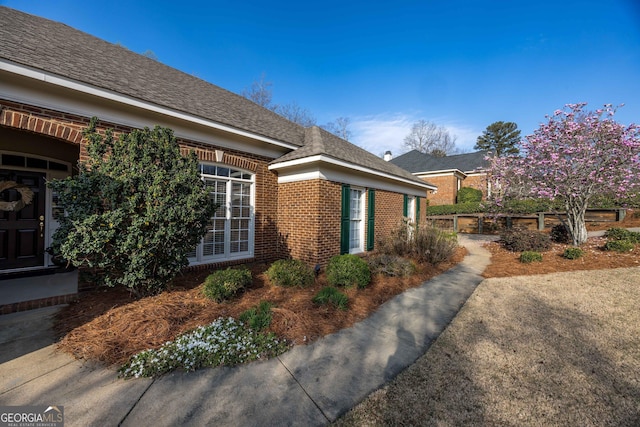 view of home's exterior featuring brick siding and fence