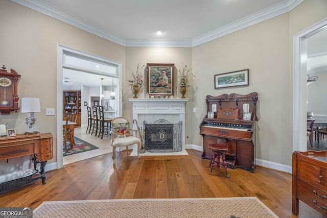 living area featuring ornamental molding, wood finished floors, baseboards, and a tile fireplace
