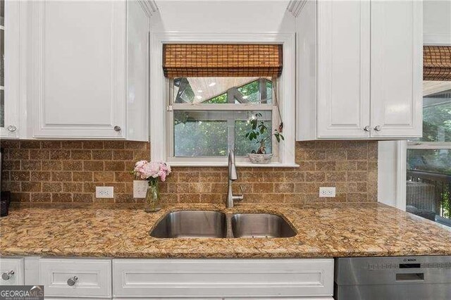 kitchen with a sink, stainless steel dishwasher, white cabinets, and healthy amount of natural light