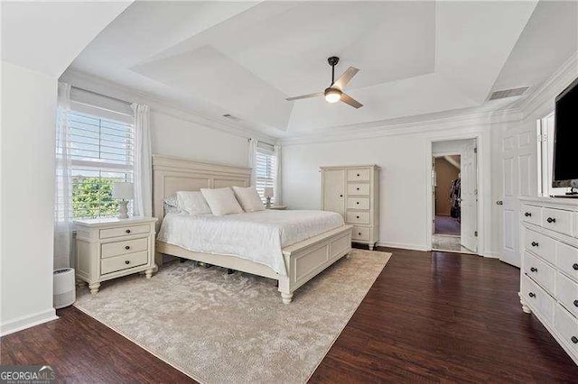 bedroom featuring a tray ceiling, wood finished floors, baseboards, and a ceiling fan