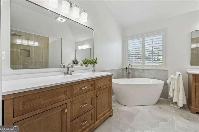 full bath with vanity, vaulted ceiling, a soaking tub, marble finish flooring, and tiled shower