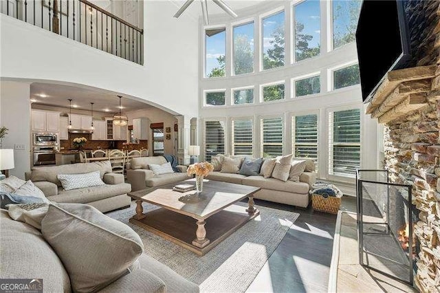 living room featuring ornate columns, arched walkways, a towering ceiling, plenty of natural light, and a ceiling fan