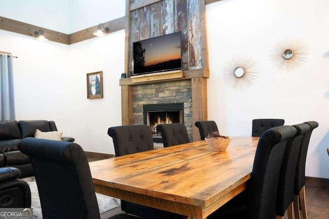 dining space featuring a stone fireplace and baseboards