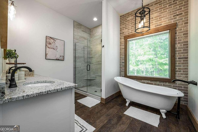 full bathroom featuring wood finished floors, a shower stall, a freestanding tub, vanity, and baseboards