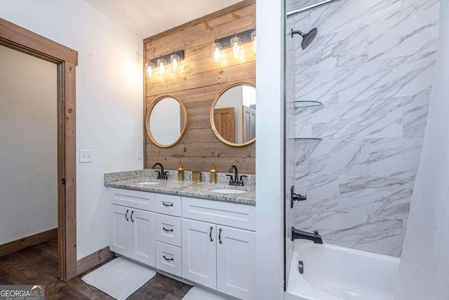 full bath with wooden walls, shower / bathtub combination, double vanity, and baseboards
