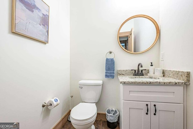 bathroom featuring toilet, vanity, and baseboards