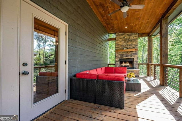 wooden terrace with an outdoor living space with a fireplace and a ceiling fan