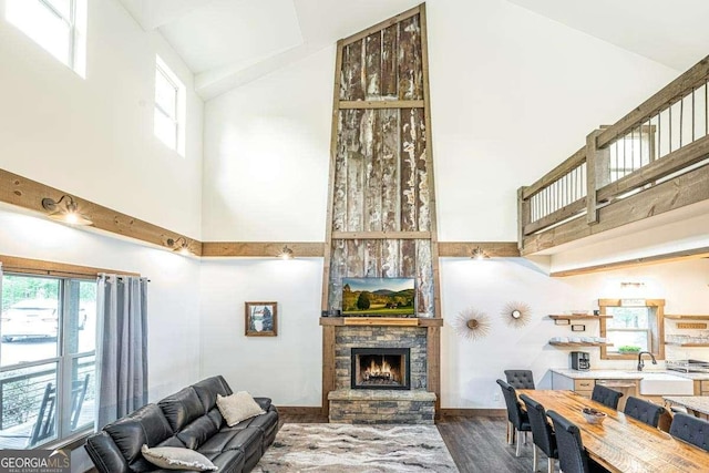 living room with high vaulted ceiling, a fireplace, wood finished floors, and baseboards