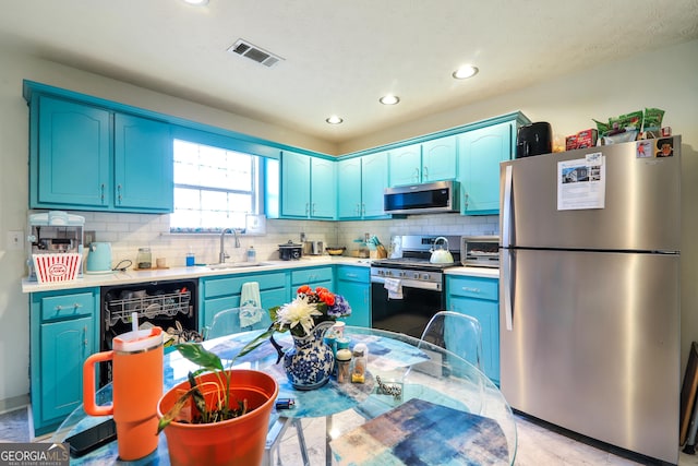 kitchen with stainless steel appliances, blue cabinetry, a sink, and recessed lighting