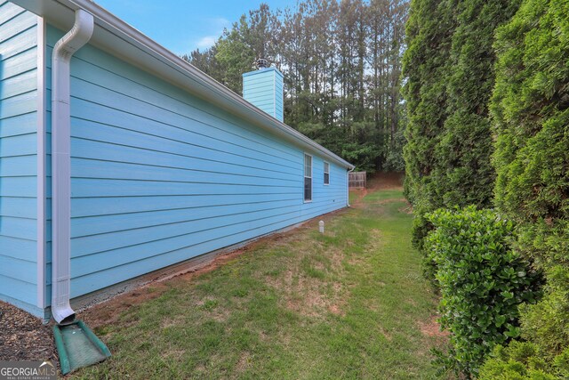 view of side of home featuring a chimney and a lawn