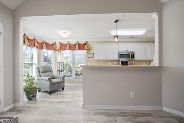 3 Bluegrass Pass, Newnan, GA 30263 - kitchen with stainless steel microwave, white cabinets, baseboards, decorative light fixtures, and light countertops