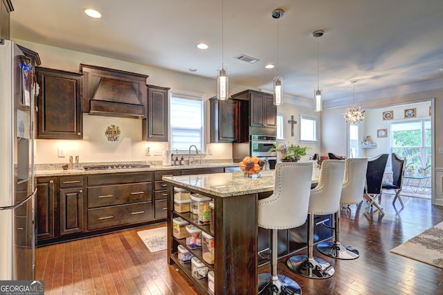 778 Firefly Ct, Griffin, GA 30223 - kitchen with dark brown cabinetry, custom range hood, a kitchen island, dark wood finished floors, and recessed lighting