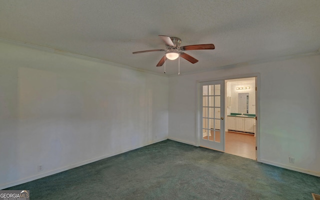 empty room with ornamental molding, dark colored carpet, a ceiling fan, and baseboards