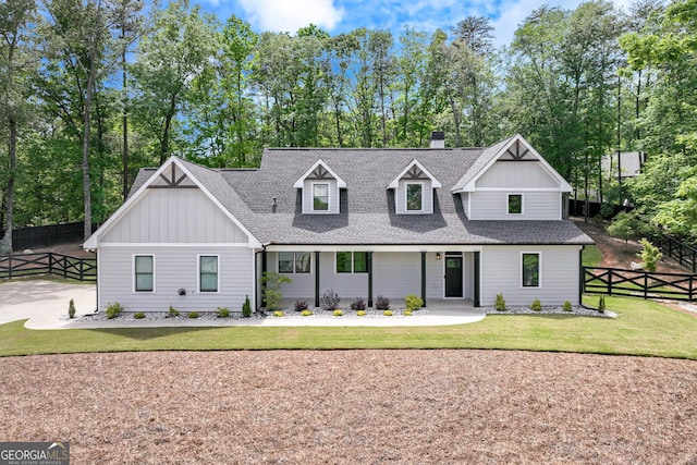 modern farmhouse featuring board and batten siding, a shingled roof, and view of scattered trees