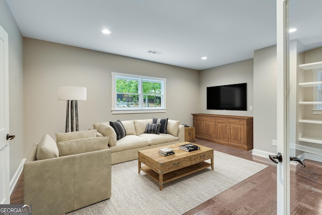 living area with wood finished floors, baseboards, recessed lighting, and built in shelves
