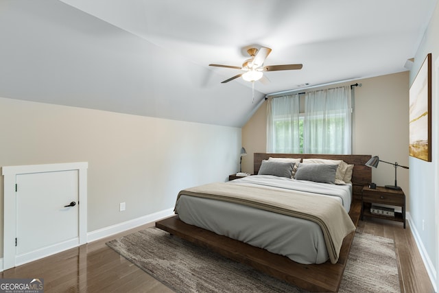 bedroom featuring wood finished floors, lofted ceiling, baseboards, and a ceiling fan