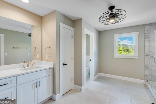 bathroom with a shower stall, vanity, toilet, baseboards, and tile patterned floors