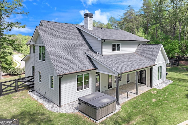 rear view of house with a shingled roof, a chimney, a patio area, and a hot tub