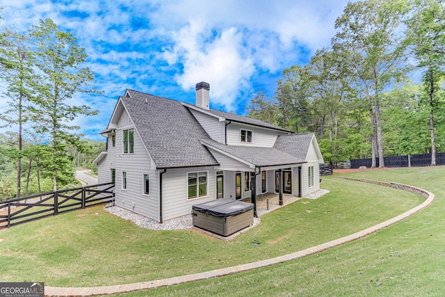 rear view of property with a shingled roof, a chimney, and a patio