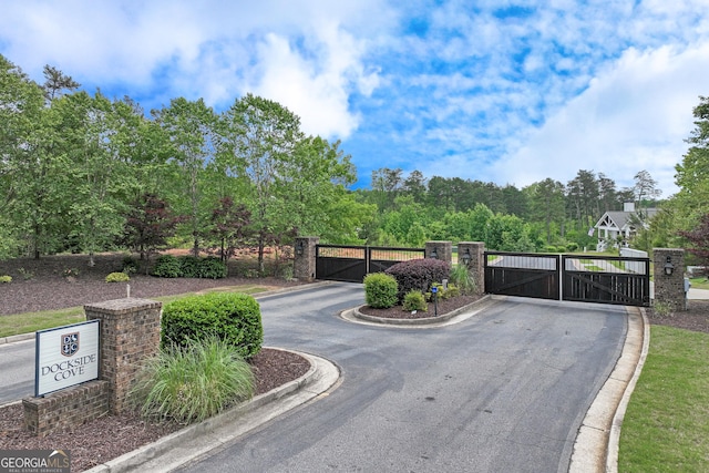 view of asphalt street featuring a gate, curbs, and a gated entry