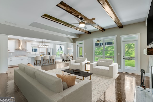 living area featuring a ceiling fan, beam ceiling, and wood finished floors