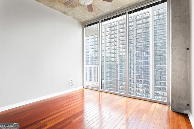 855 Peachtree St NE Unit 2203, Atlanta, GA 30308 - empty room with a wall of windows, hardwood / wood-style floors, a ceiling fan, and baseboards