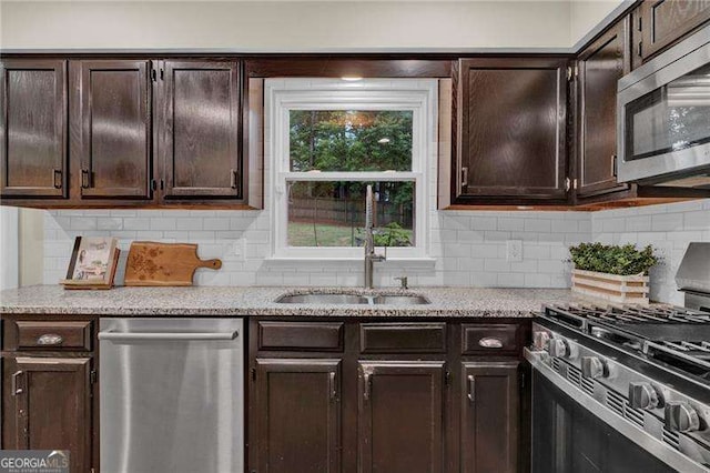 kitchen with stainless steel appliances, dark brown cabinets, a sink, and decorative backsplash