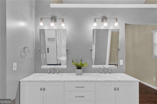 full bath with double vanity, wood finished floors, and baseboards